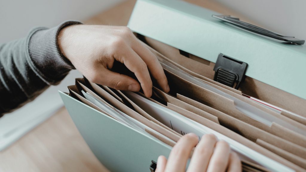 Hands sorting documents in a file organiser